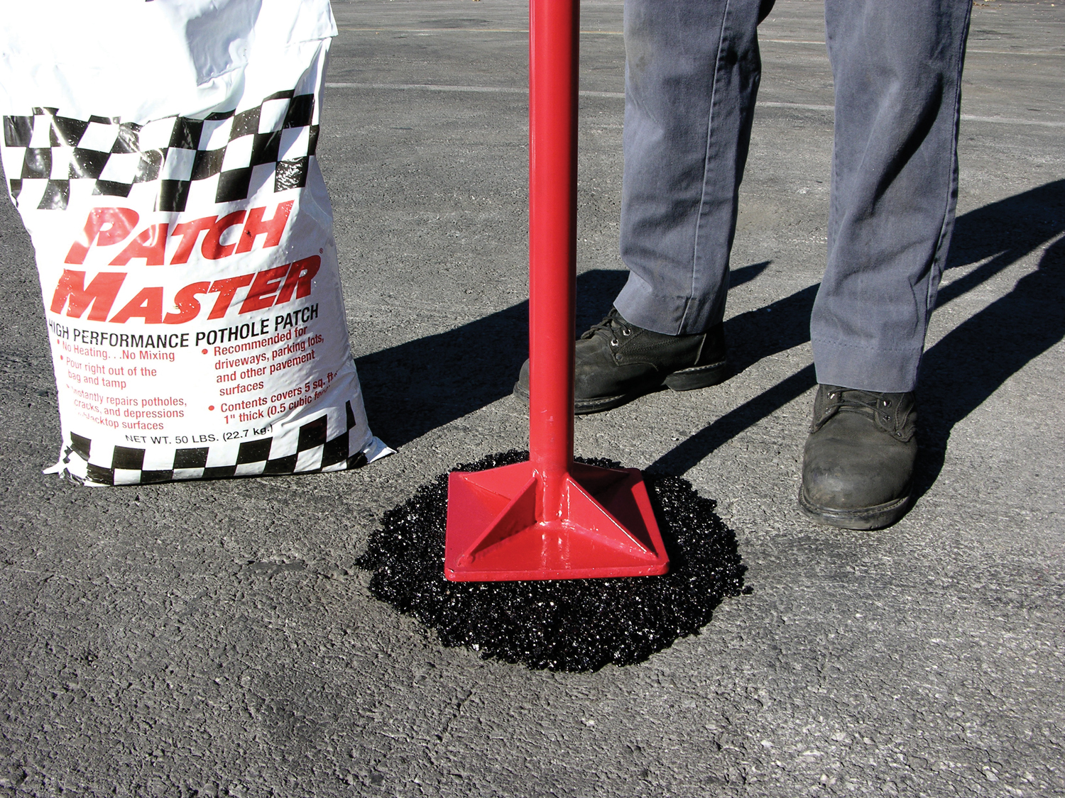 Sealcoating contractor applying traffic marking paint to an arrow in a freshly sealcoated parking lot.