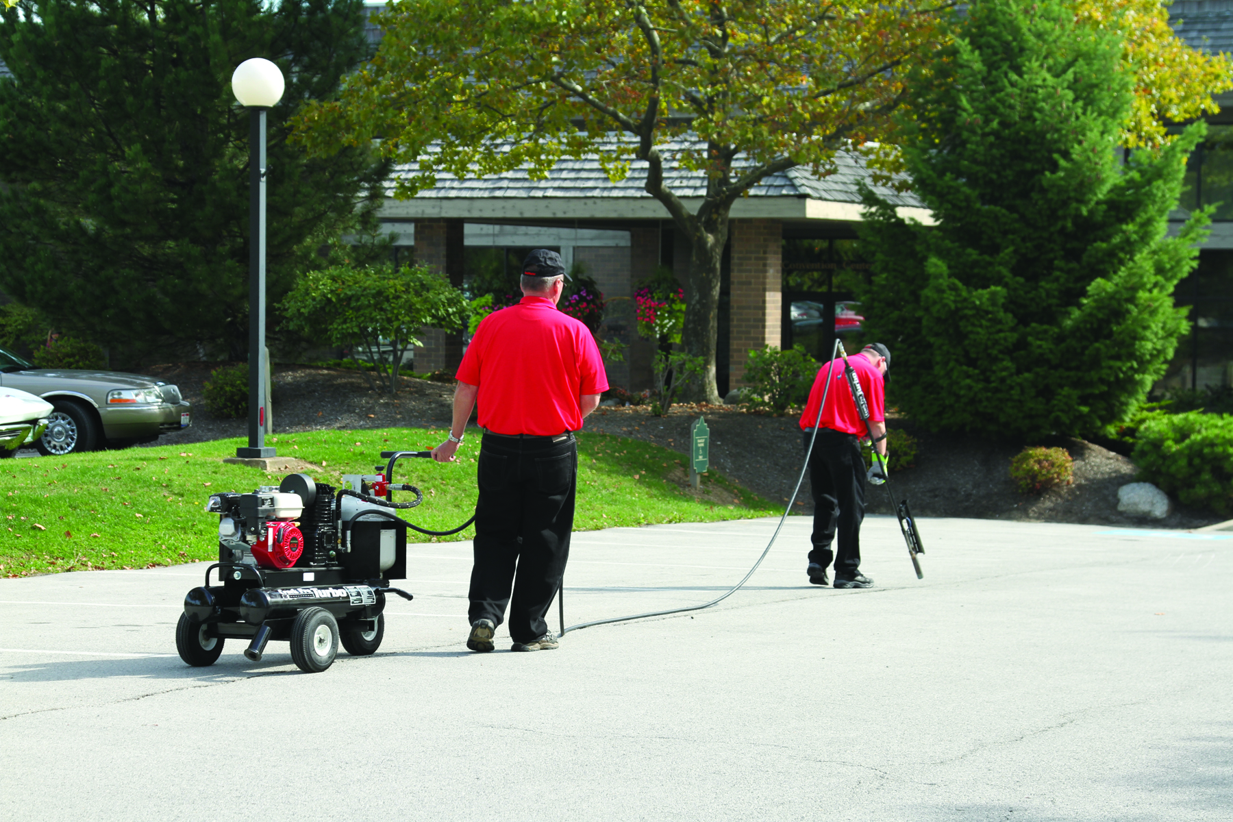 Local Sealcoating contractor applying SealMaster FlexMaster Crack Sealant (Cold-applied pourable crack sealant) into a crack an asphalt driveway or parking lot