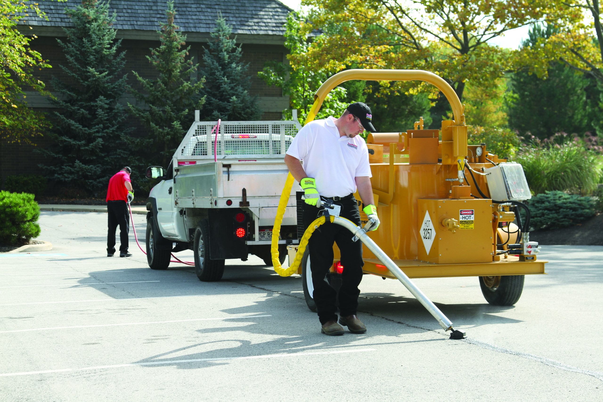 Sealcoating contractor operating SealMaster equipment to fill cracks in a parking lot.