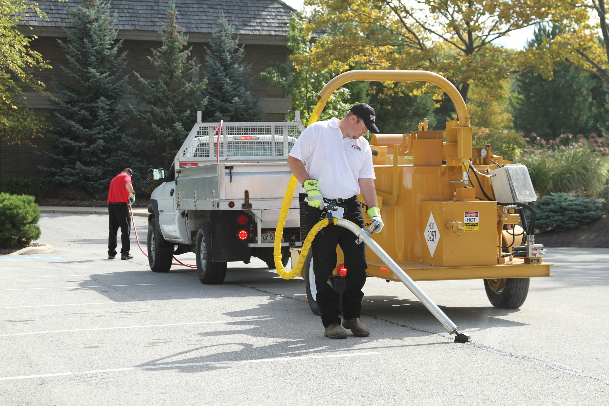 SealMaster Fast-Dry Traffic Paint (White and Yellow) being applied on a parking lot by a local sealcoating contractor with a line striping machine.