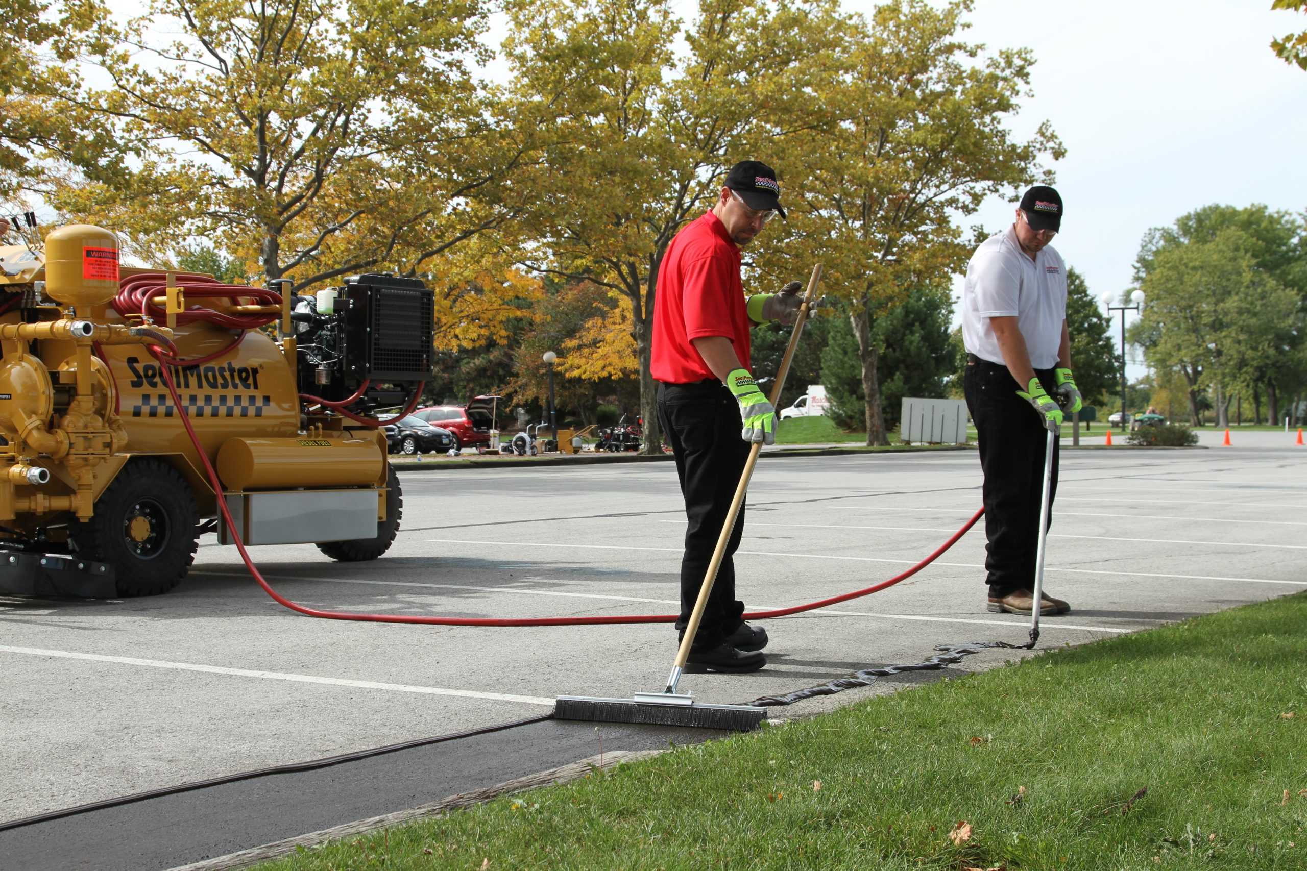 Local Sealcoating contractor applying SealMaster FlexMaster Crack Sealant (Cold-applied pourable crack sealant) into a crack an asphalt driveway or parking lot