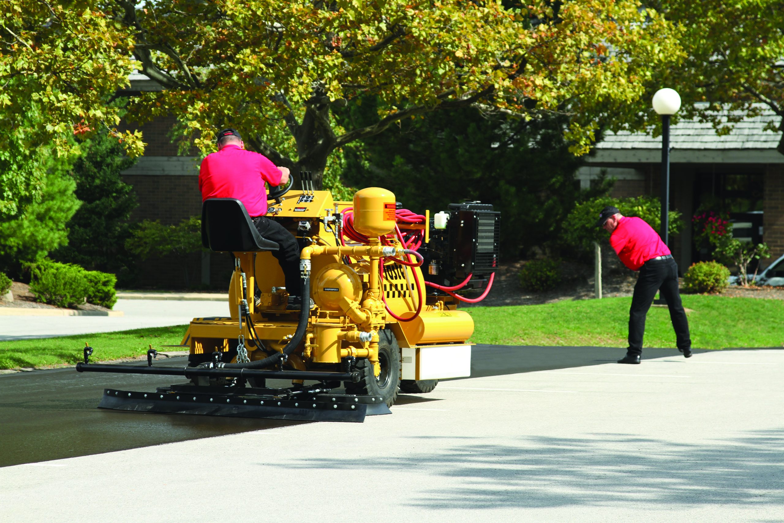 Sealcoating contractors using SealMaster equipment while sealcoating a parking lot.