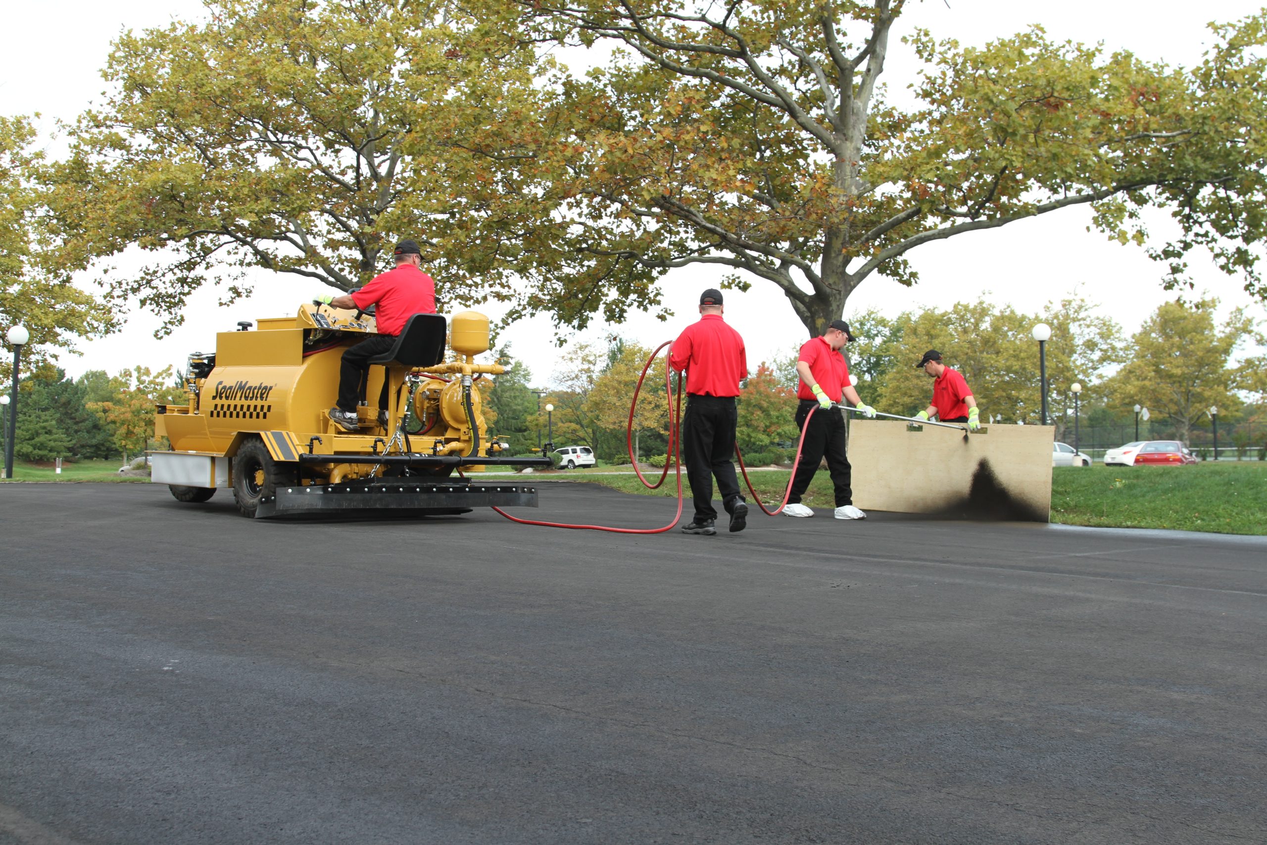 Sealcoating contractor applying traffic marking paint to an arrow in a freshly sealcoated parking lot.