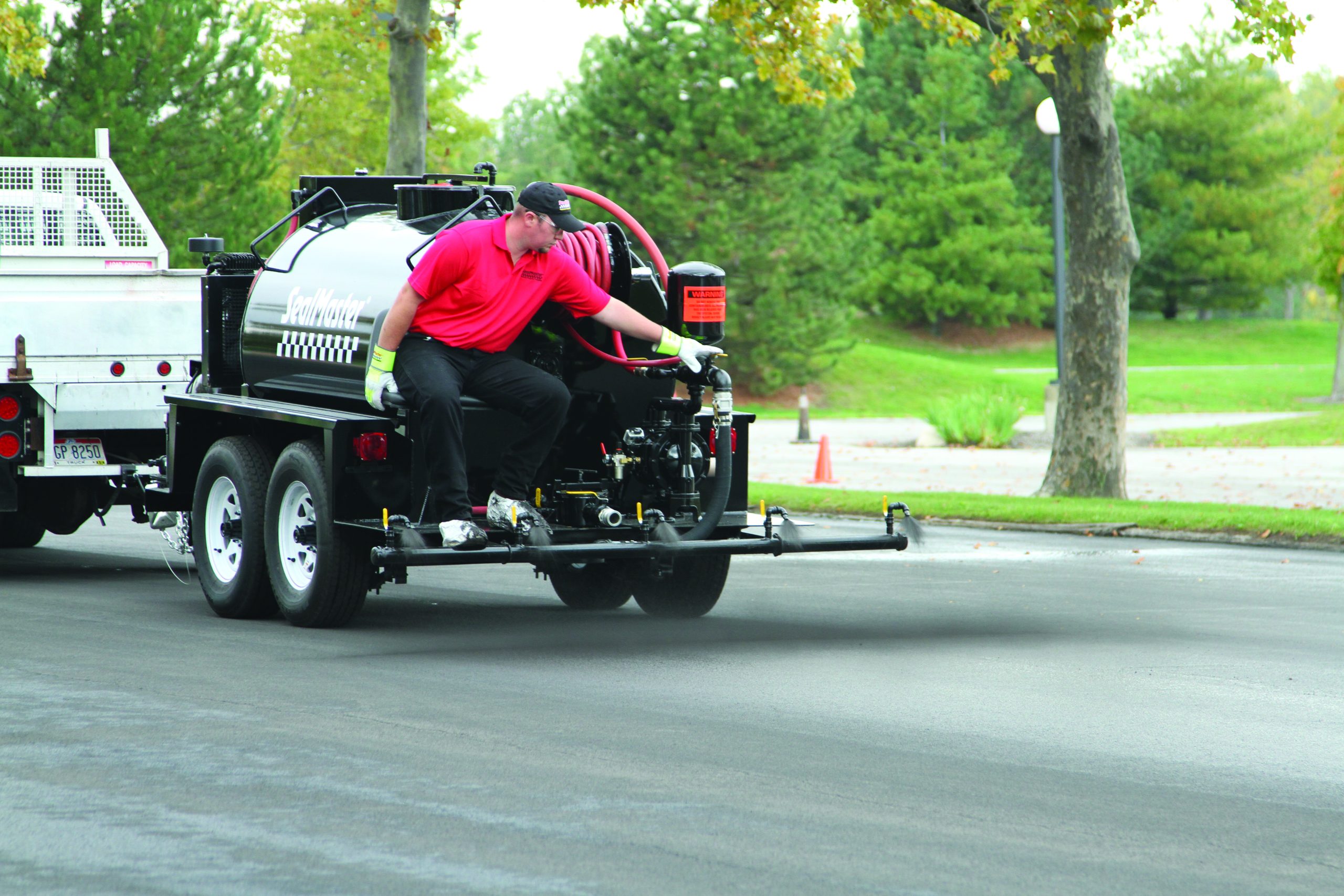 Sealcoating contractor using SealMaster equipment to sealcoat a parking lot.