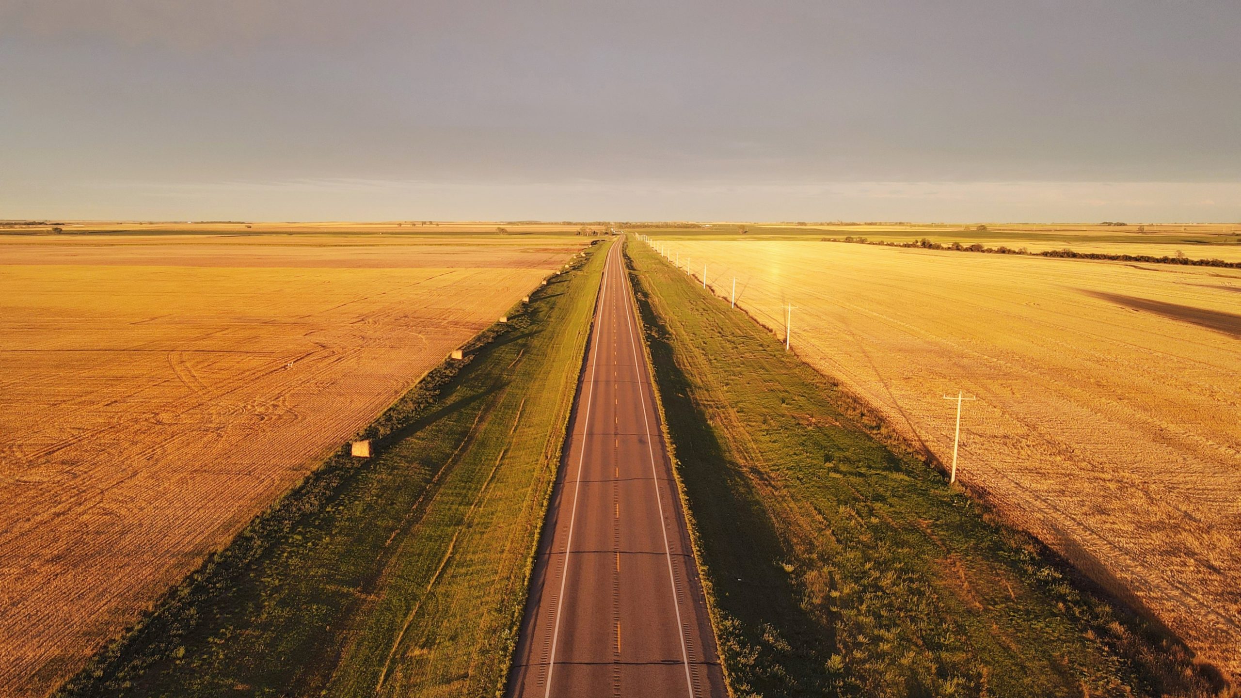 An aerial view of a long pathway through a vast, open landscape on a sunny day