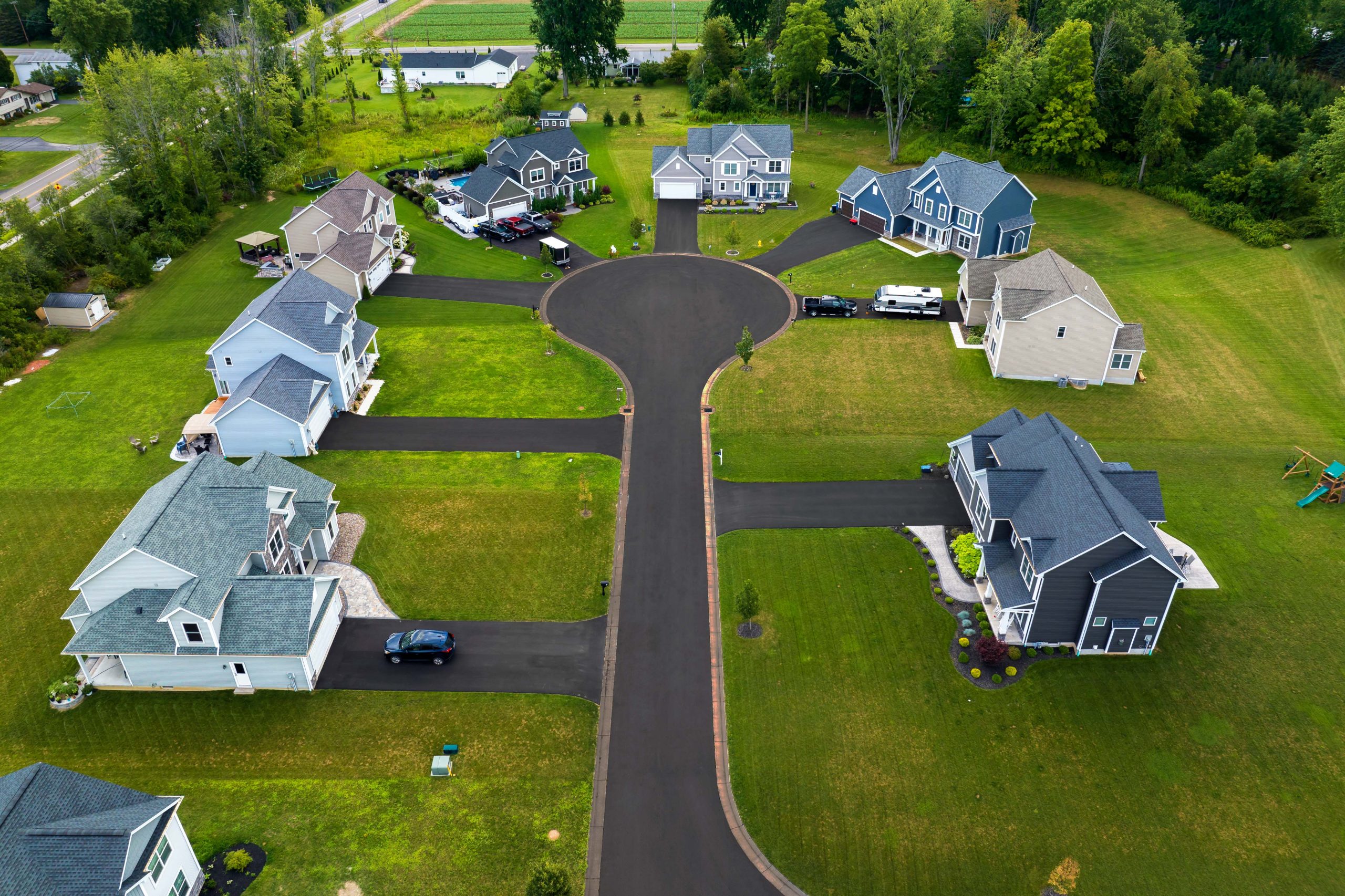 Aerial view of a fresh sealcoated road and driveways in residential houses.