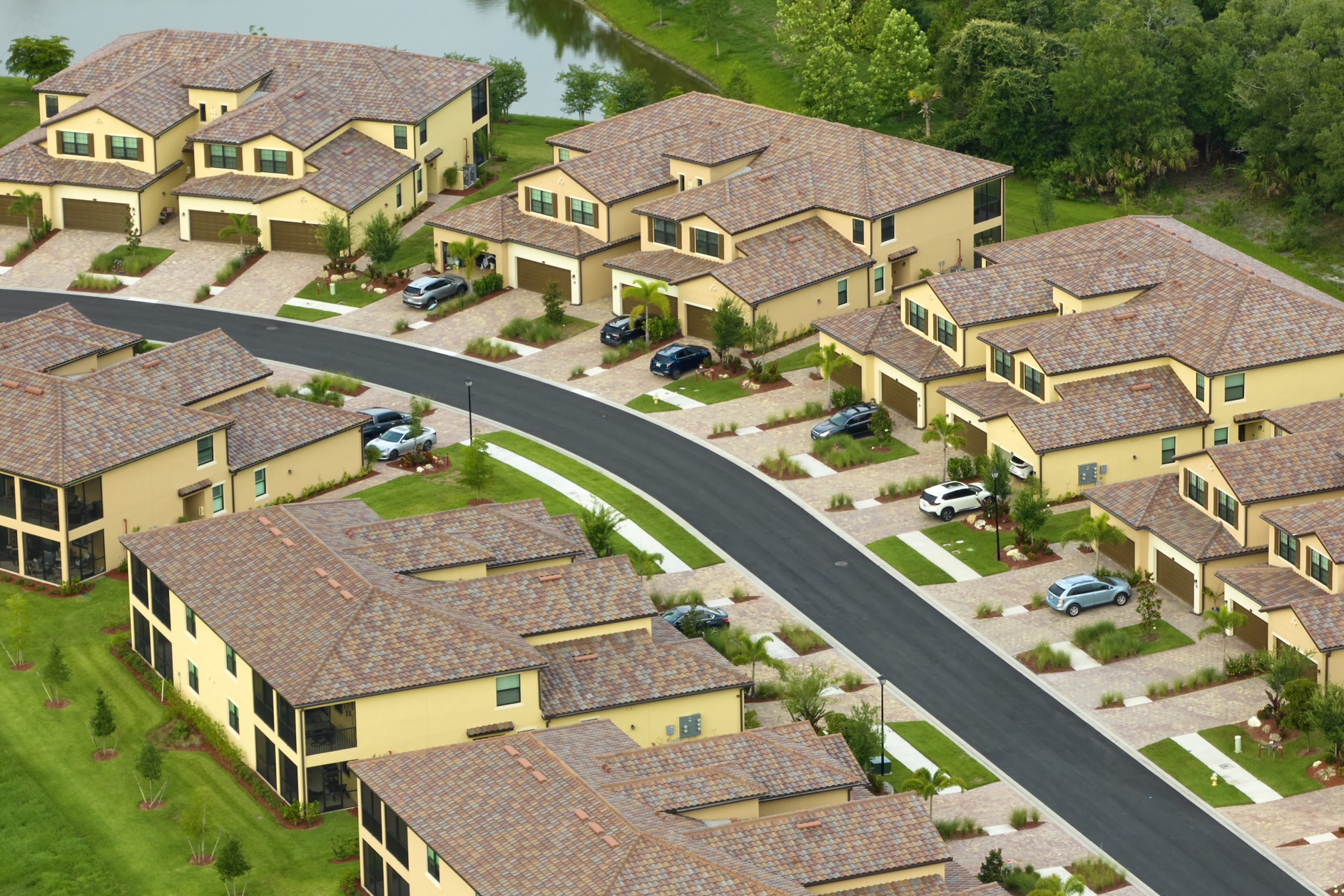 Aerial view of family houses in Florida closed suburban area. Real estate development in american suburbs. Freshly sealcoated roads and riveways.