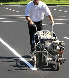 SealMaster Liquid Thermoplastic Traffic Marking Paint (White and Yellow) being applied by a local sealcoating contractor using a line striping machine on a parking lot.