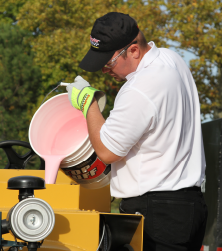 SealMaster TopTuff Polymer Additive being poured into a sealcoating machine full of asphalt sealer by a local sealcoating contractor.