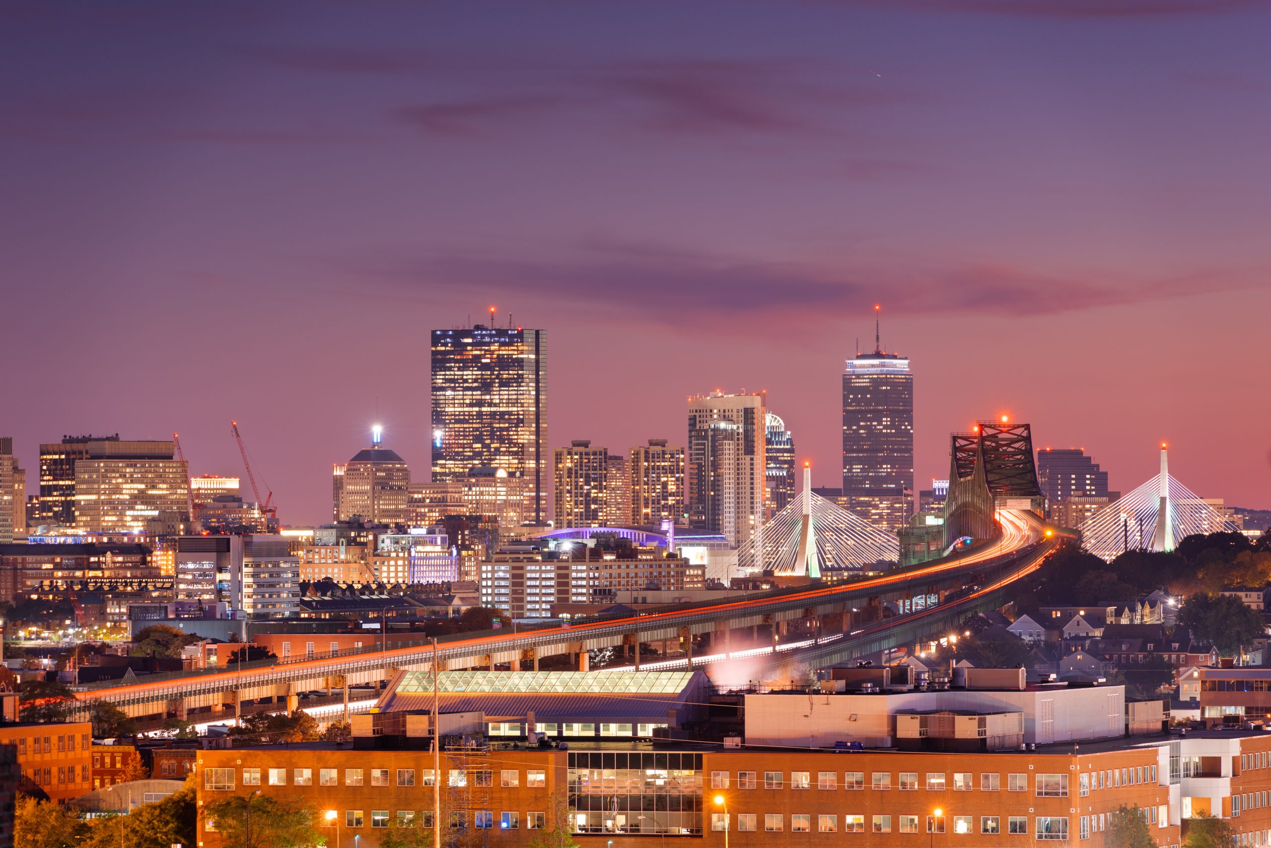 Boston, Massachusetts, USA skyline with bridges and highways at dusk.