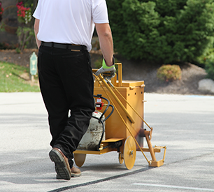 Sealcoating contractor applying traffic marking paint to an arrow in a freshly sealcoated parking lot.