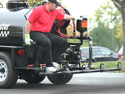 SealMaster FlexMaster Crack Sealant (Cold-applied pourable crack sealant) being applied to a crack in asphalt driveway by a local sealcoating contractor.