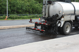 Asphalt sealcoating machine applies OptiPave pavement sealer to the road.