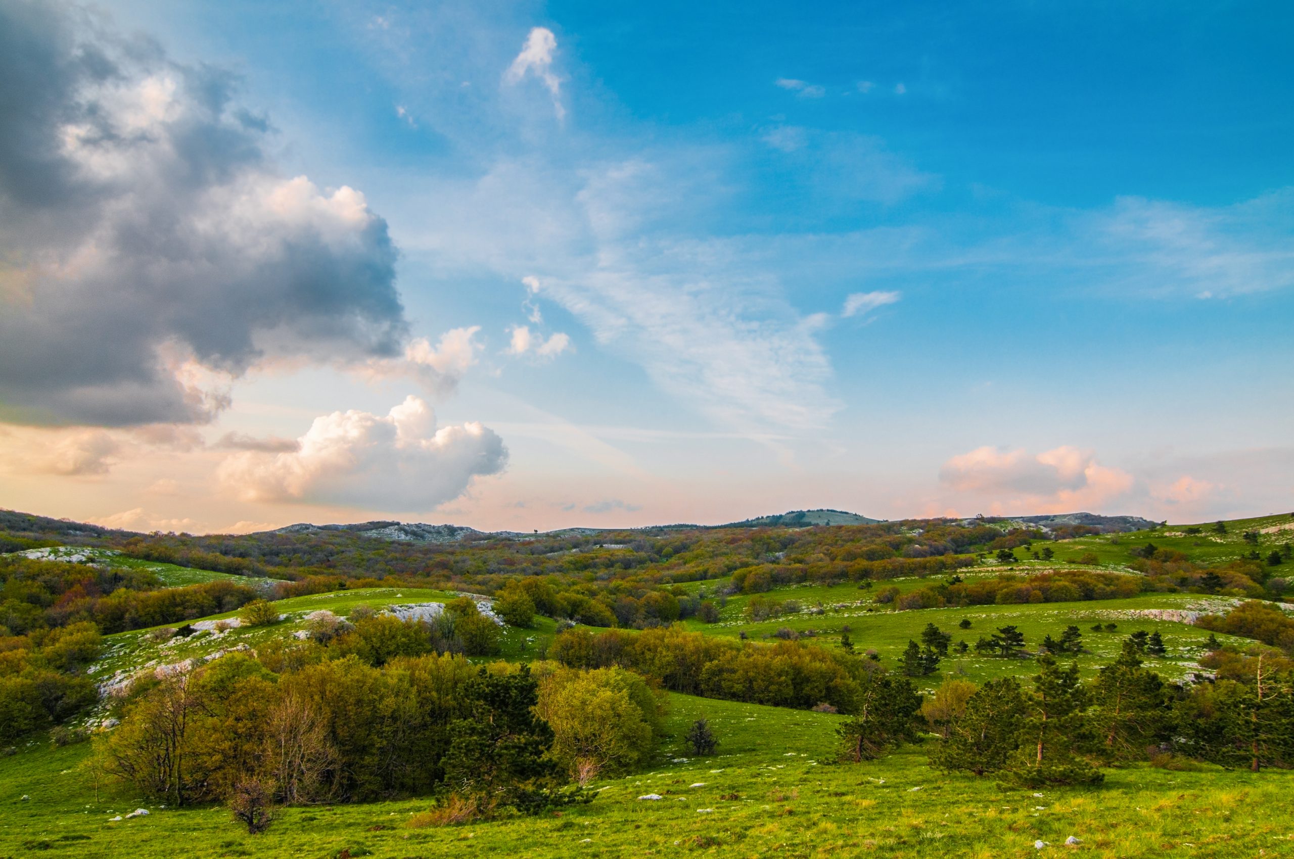 Picturesque landscape, rain clouds, mountains covered with green plants, country road passes among hills