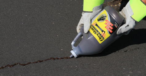 SealMaster FlexMaster Crack Sealant (Cold-applied pourable crack sealant) being applied to a crack in asphalt driveway by a local sealcoating contractor.