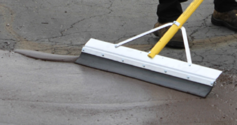 SealMaster GatorPave Patching Material being applied by a local sealcoating contractor using a squeegee in a parking lot.