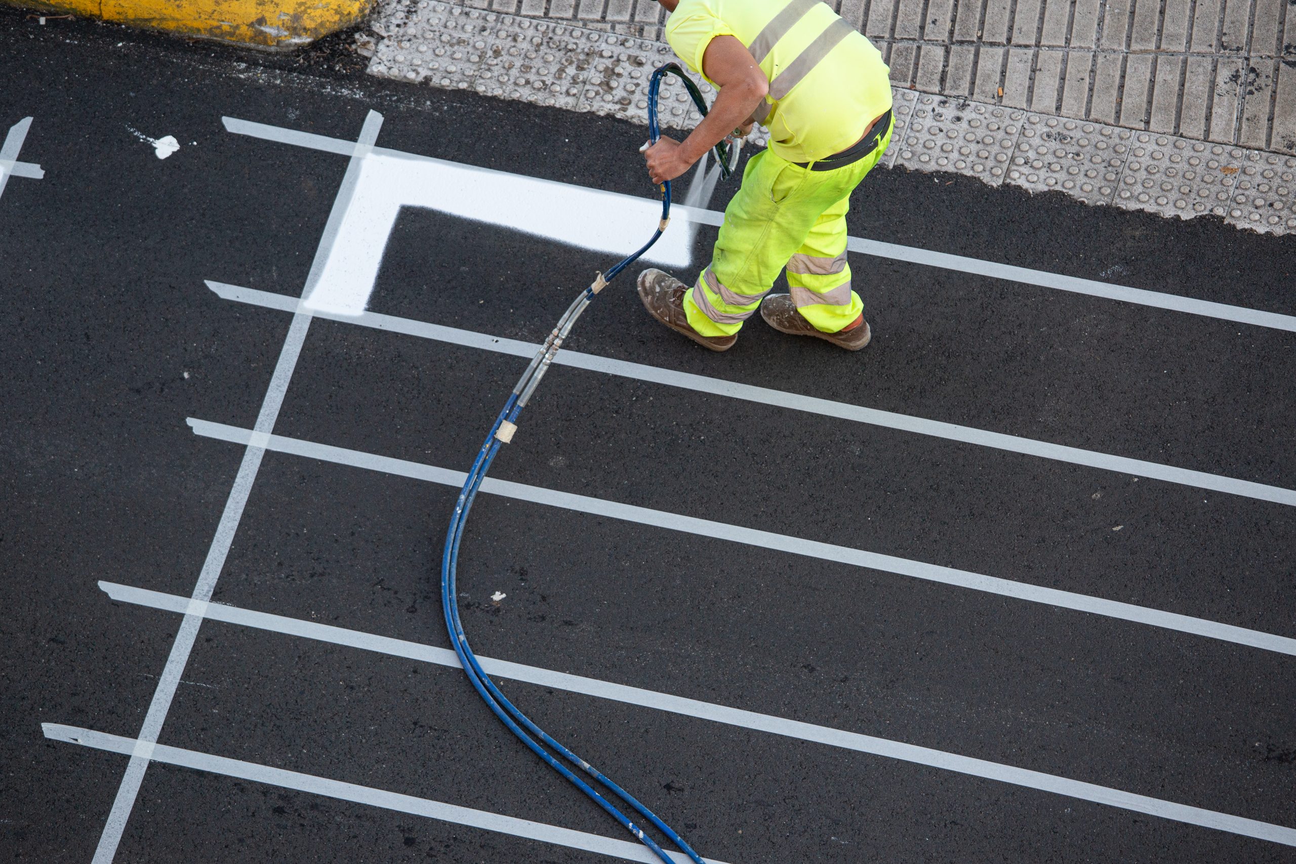 Contractor painting a pedestrian crosswalk road. SealMaster Local Sealcoating